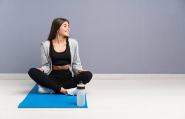 Genç sporcu kadın yere oturmuş yere bakıyor.