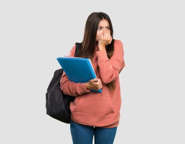 Not defterleri tutan genç bayan gergin ve korkmuş. Gri arka planda el ele tutuşuyor.