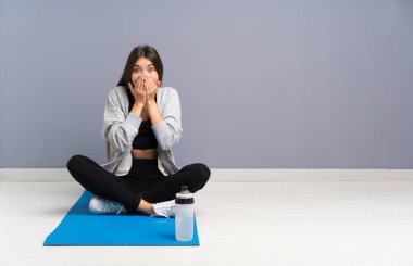 Genç spor kadın sürpriz yüz ifadesi ile paspas ile katta oturan