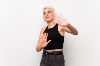 Teenager girl with short hair over white wall nervous stretching hands to the front