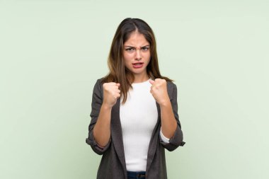 İzole edilmiş yeşil arka planda ceketli esmer kız kötü bir durum yüzünden hayal kırıklığına uğradı.