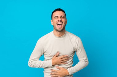 Soyutlanmış mavi arka planı olan genç adam çok gülümsüyor.