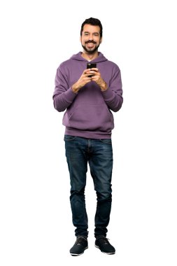Sweatshirt ile yakışıklı adam tam uzunlukta çekim izole beyaz arka plan üzerinde mobil ile bir mesaj gönderme