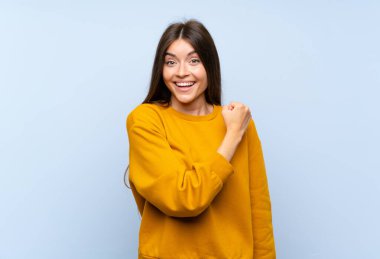 Kafkas genç kadın izole mavi duvar üzerinde bir zafer kutluyor