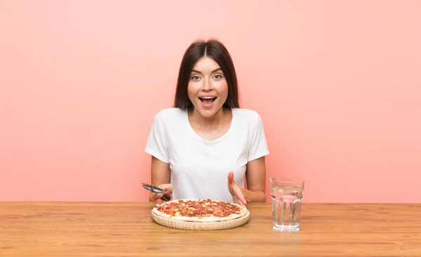 Mujer joven con una pizza en una mesa — Foto de Stock