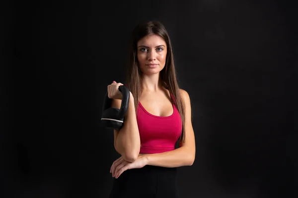 Mujer deportiva joven haciendo levantamiento de pesas sobre fondo negro aislado —  Fotos de Stock