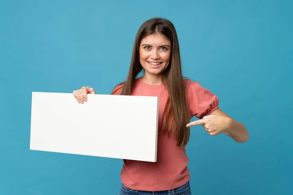 Mladá Žena Izolovaném Modrém Pozadí Drží Prázdný Bílý Štítek Pro — Stock fotografie