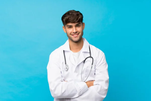 Joven Hombre Guapo Sobre Fondo Azul Aislado Con Bata Médico — Foto de Stock