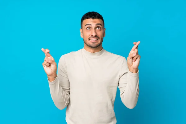 Ung Man Över Isolerad Blå Bakgrund Med Fingrar Korsning Och — Stockfoto