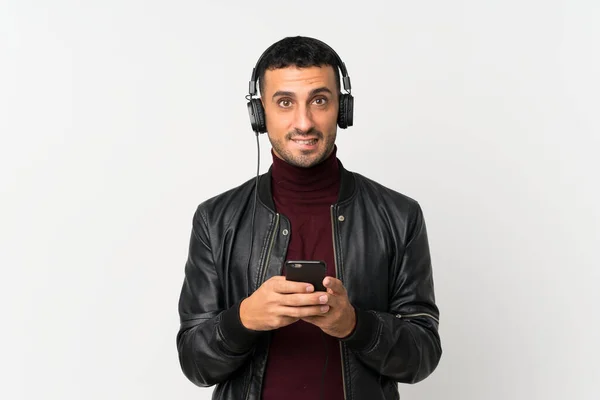 Молодий Чоловік Над Ізольованим Білим Тлом Допомогою Мобільного Телефону Навушниками — стокове фото
