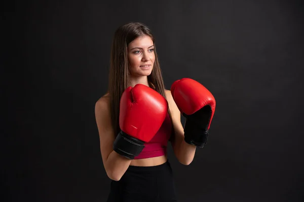 Mujer deportiva joven con guantes de boxeo sobre fondo negro aislado — Foto de Stock