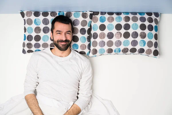 Man in bed in top view laughing