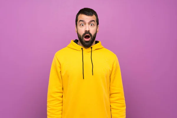 Handsome man with yellow sweatshirt with surprise facial expression