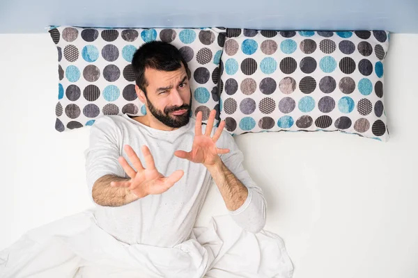 Man in bed in top view nervous stretching hands to the front