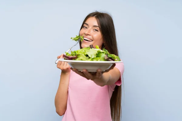 年轻女子与沙拉在孤立的蓝色背景 — 图库照片