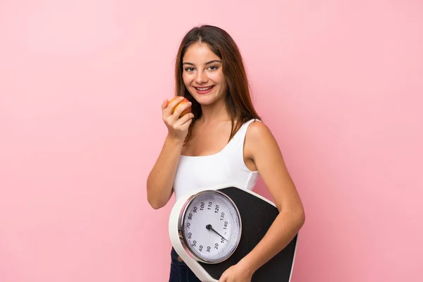 Young pretty girl with weighing machine and with an apple over i — Stock Photo, Image