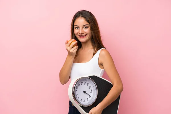 Joven chica bonita con máquina de pesaje y con una manzana sobre i — Foto de Stock