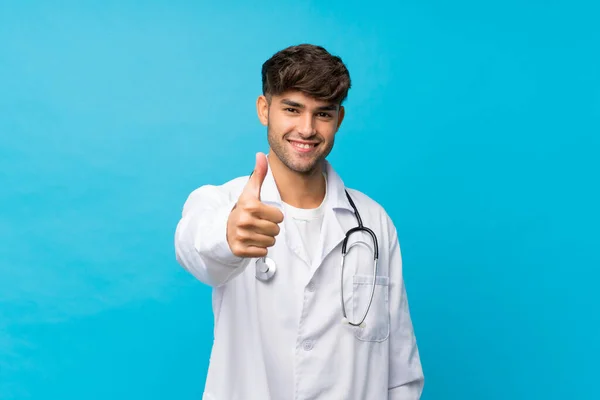 Joven Hombre Guapo Sobre Fondo Azul Aislado Con Bata Médico —  Fotos de Stock