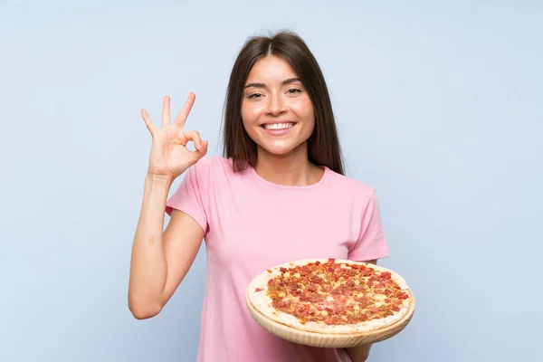 Bonita Joven Sosteniendo Una Pizza Sobre Una Pared Azul Aislada — Foto de Stock