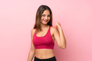 Soyutlanmış pembe arka planda genç bir kız halter yapıyor.