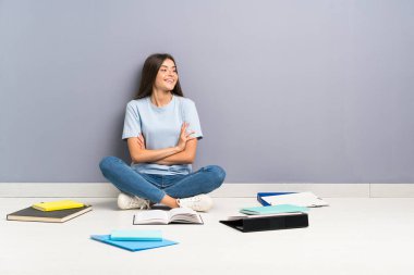 Yerde gülen birçok kitap ile genç öğrenci kadın