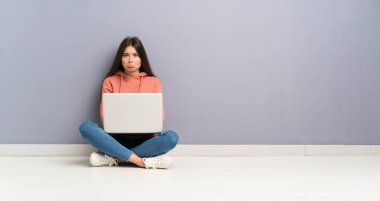 Dizüstü bilgisayarı olan genç kız üzgün.