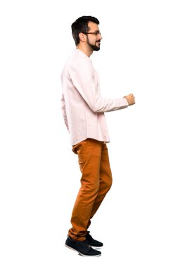 Sakallı yakışıklı bir adamın izole edilmiş beyaz arka planda yürürken tam boy fotoğrafı.