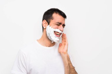 Adamın sakalını diş ağrısı olan beyaz bir arka plan üzerinde tıraş ediyor.