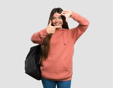 Yüzüne odaklanan not defterleri tutan genç bir bayan öğrenci. İzole edilmiş gri arkaplan üzerindeki çerçeve sembolü