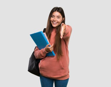 Genç bayan not defterlerini tutuyor. Gri arka planda iyi bir anlaşma yapmak için el sıkışıyor.