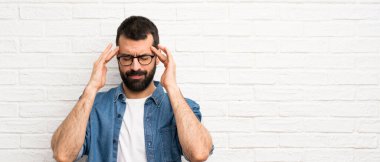 Beyaz tuğlalı duvarın üzerinde sakallı yakışıklı bir adam.