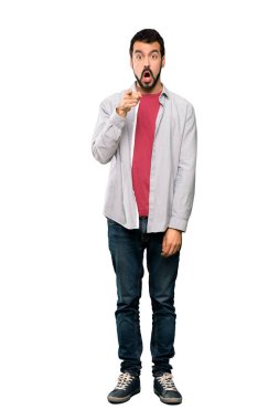 Sakallı, yakışıklı bir adamın, izole edilmiş beyaz arka plan üzerinde şaşırmış ve ön tarafı işaret ettiği uzun bir fotoğraf.