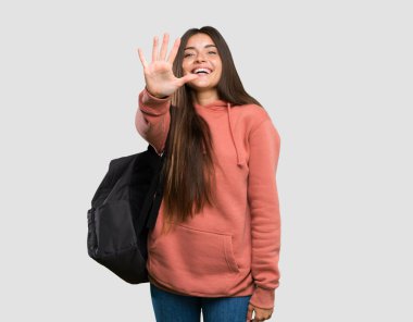 Elinde not defterleri olan genç bir bayan. İzole edilmiş gri arka planda parmakları olan beş kişi sayıyor.