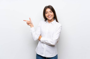 İzole edilmiş beyaz arka planda genç bir kadın, parmağını yana doğru gösteriyor.