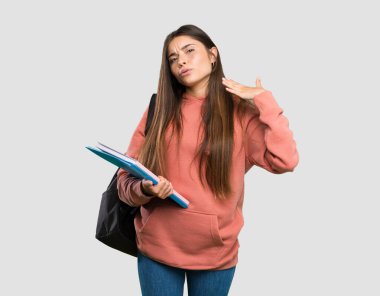 İzole gri arka plan üzerinde yorgun ve hasta ifade ile defter tutan genç öğrenci kadın