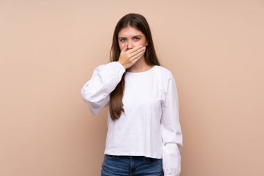 İzole edilmiş arka planı olan genç bir kız elleriyle ağzını kapatıyor.