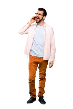 Sakallı, yakışıklı bir adamın izole edilmiş beyaz arka planda cep telefonuyla sohbet ederken tam boy görüntüsü.