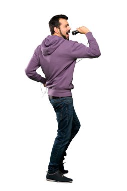 Tişörtlü yakışıklı adam mikrofonla şarkı söylüyor.