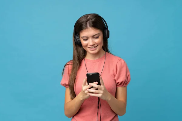 Νεαρή Γυναίκα Πάνω Από Απομονωμένο Μπλε Φόντο Χρησιμοποιώντας Κινητό Ακουστικά — Φωτογραφία Αρχείου