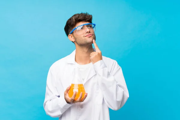 Junger Gutaussehender Mann Vor Isoliertem Blauem Hintergrund Mit Wissenschaftlichem Reagenzglas — Stockfoto