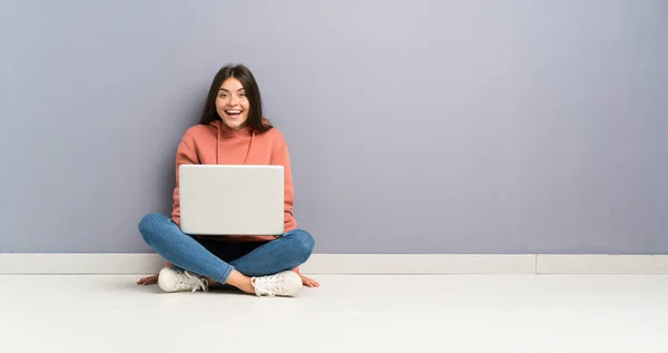 年轻的学生女孩与笔记本电脑在地板上与惊喜的面部表情 — 图库照片