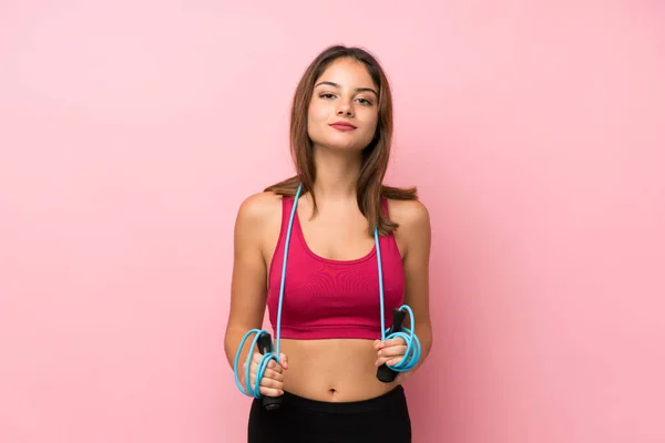 Young sport girl over isolated pink background with jumping rope