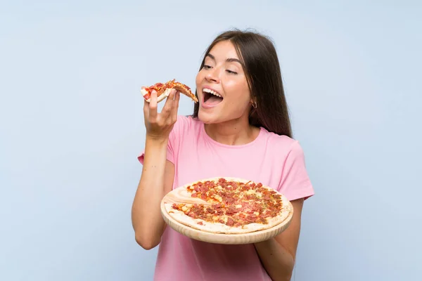 Ładna młoda dziewczyna trzyma pizzę na białym tle niebieską ścianę — Zdjęcie stockowe