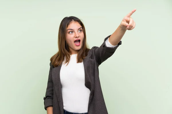 Menina Morena Jovem Com Blazer Sobre Fundo Verde Isolado Apontando — Fotografia de Stock