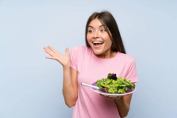 Mujer Joven Con Ensalada Sobre Fondo Azul Aislado Con Expresión — Foto de Stock