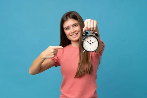 Ung Kvinna Över Isolerad Blå Bakgrund Håller Vintage Väckarklocka — Stockfoto