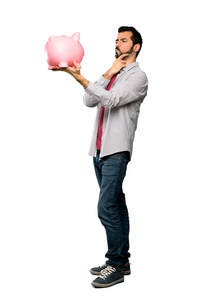 Hombre guapo con barba sosteniendo una alcancía — Foto de Stock