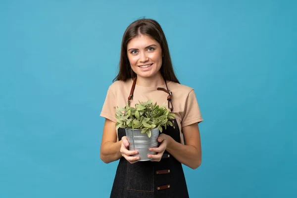 Jovem Mulher Sobre Isolado Azul Fundo Tomando Vaso Flores — Fotografia de Stock