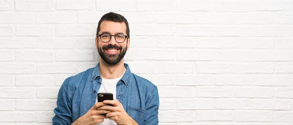 Beyaz Tuğla Duvarın Üzerinde Sakallı Yakışıklı Bir Adam Cep Telefonuyla — Stok fotoğraf