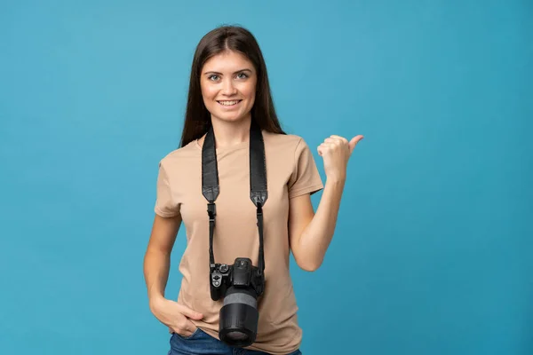 Jovem Mulher Sobre Fundo Azul Isolado Com Uma Câmera Profissional — Fotografia de Stock